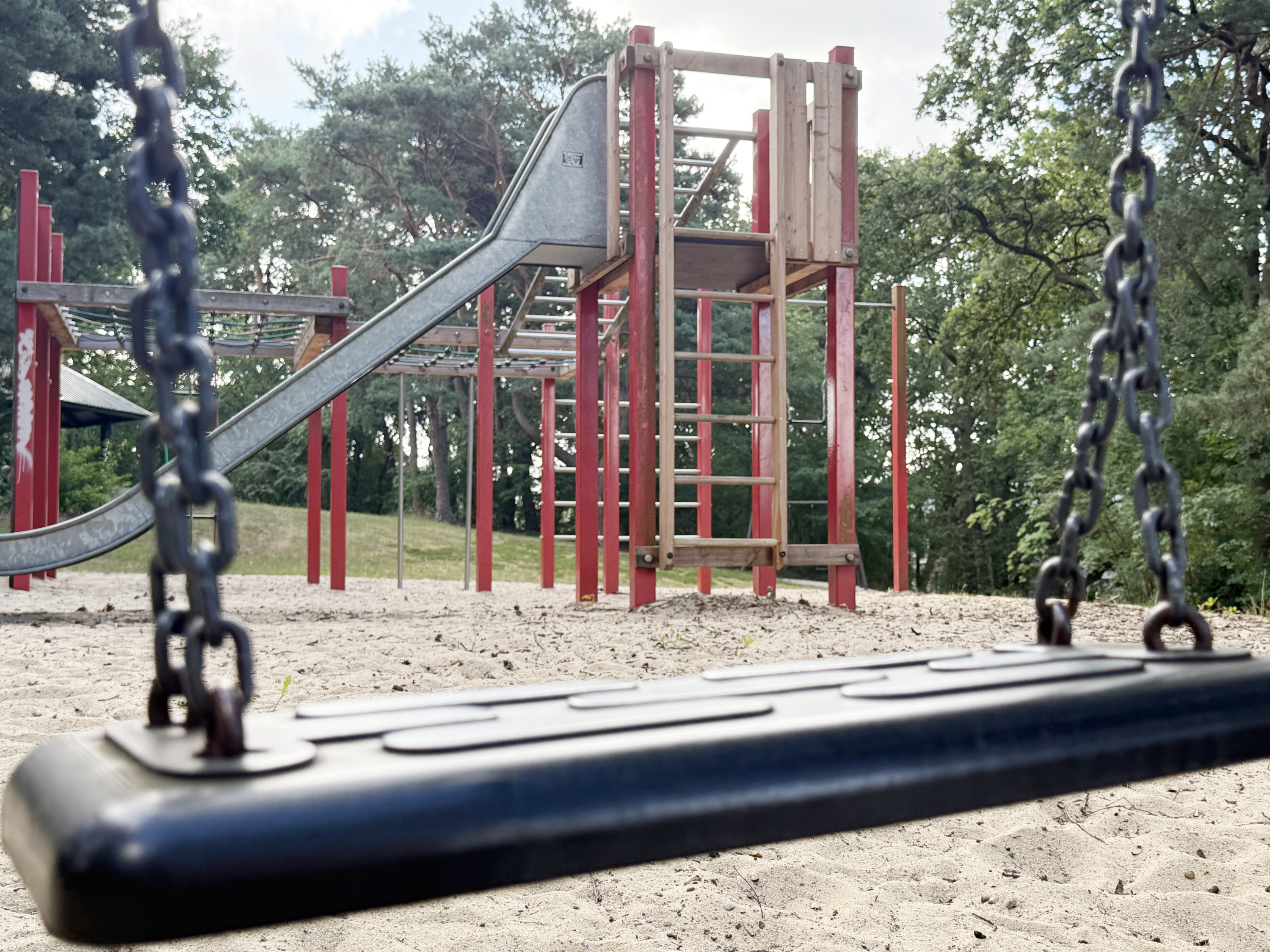 Spielturm mit Rutsche, bildlich eingerahmt von einer Schaukel