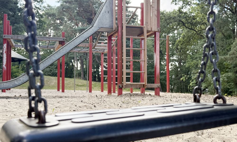 Spielturm mit Rutsche, bildlich eingerahmt von einer Schaukel